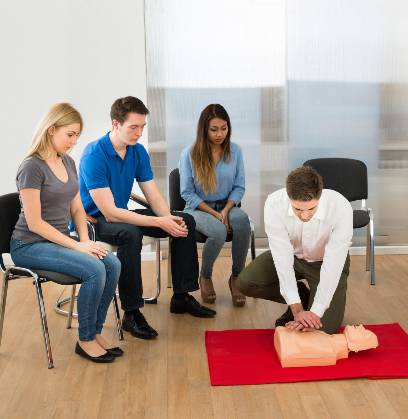 Office worker practices CPR on a manikin.